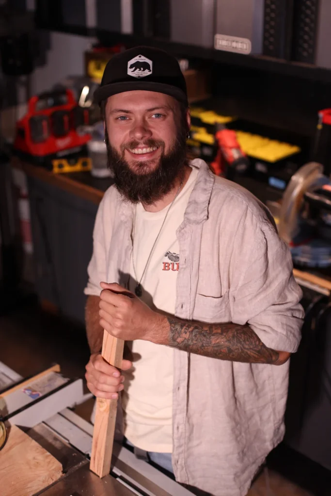 Alex Titov holding a wooden piece in his workshop