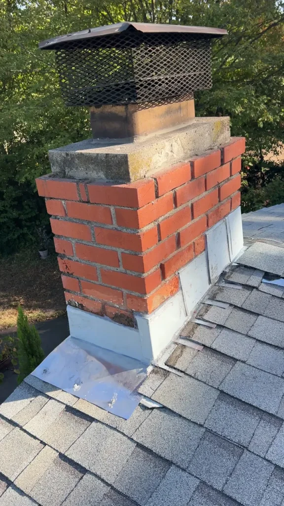 Brick chimney with new metal flashing after the repair