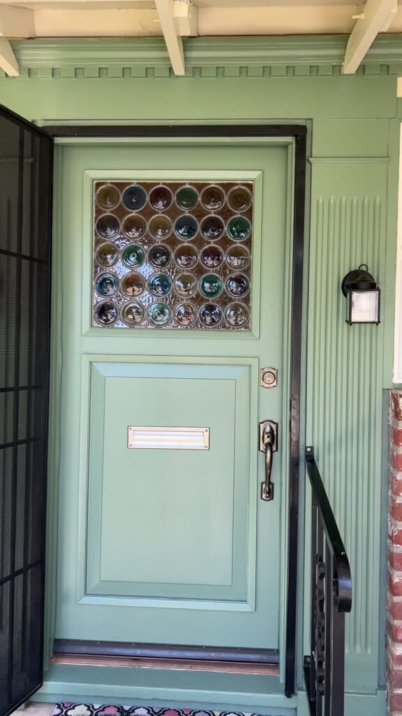 Restored pale green front door with decorative glass